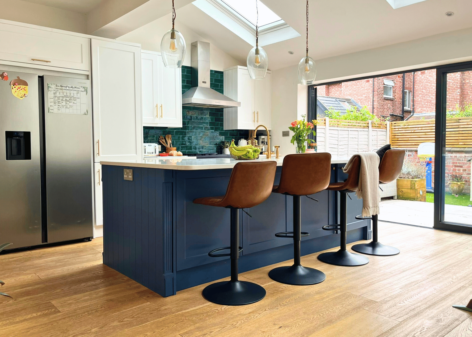 Modern kitchen with blue island, bar seating, and natural light – online interior design support from Spaces by Spaces by Kelly Interior Design